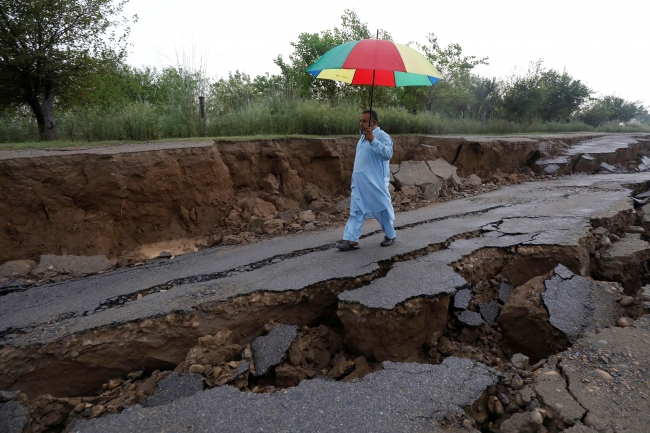 Deprem sonrası çatlak oluşan yol üzerinde yürüyen bir Pakistanlı. Fotoğraf: Reuters