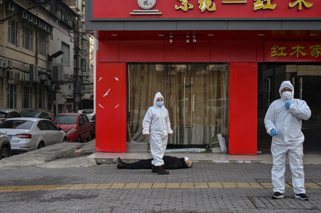 Koronavirüs sebebiyle hayatını kaybeden bir Wuhanlı yerde yatıyor. | Fotoğraf: AFP