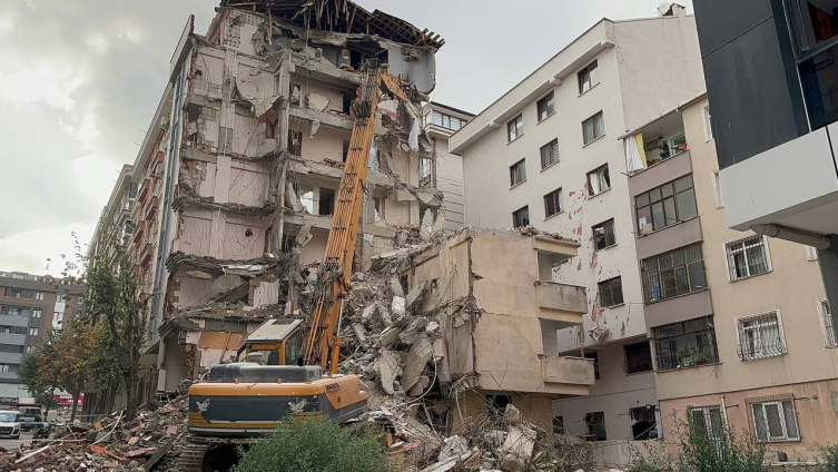 Yıkımı yapılan binadan kopan molozlar arkadaki apartmana zarar verdi