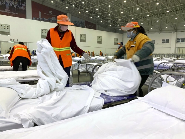 Wuhan'da yatakhaneye çevrilen kongre merkezinde çalışan görevliler | Fotoğraf: AP